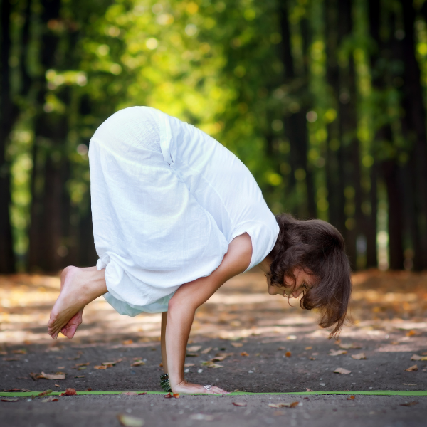 Woman in the wilderness, practising crow pose 